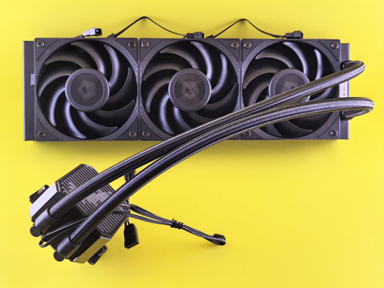 services-04 A close-up of a computer cooling system with three fans on a vibrant yellow background.