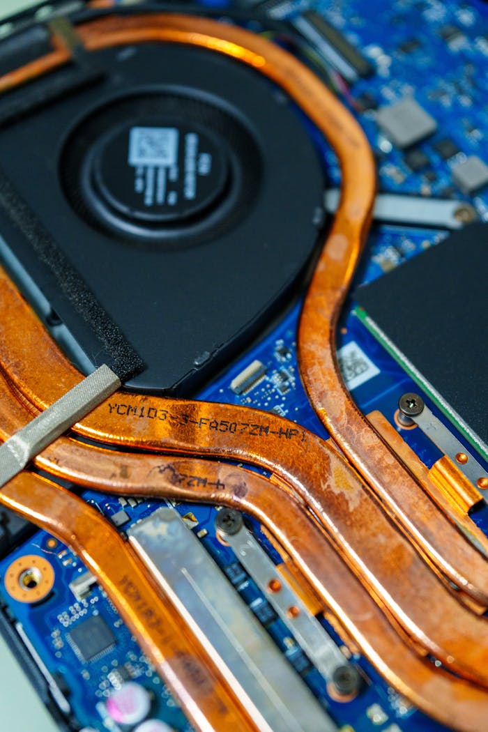 Detailed view of a laptop's cooling system showing copper heat pipes and intricate circuitry.